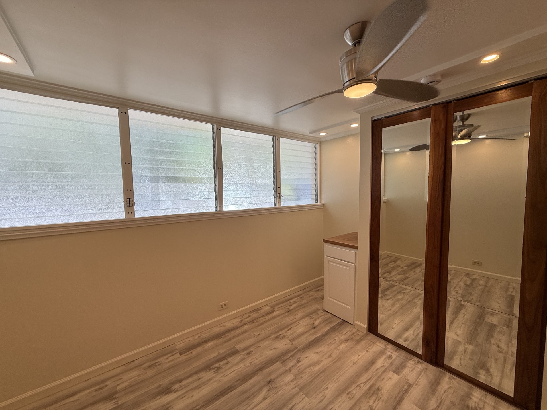 A room with a ceiling fan and a window with blinds.